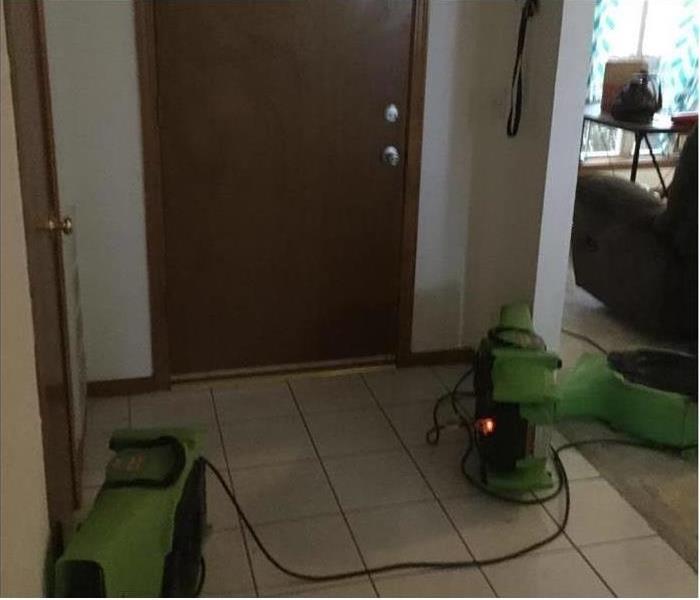 Restoration machines are cleaning water damage in a home.
