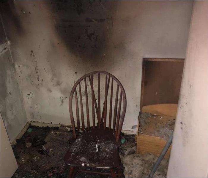 Chair burned inside an empty room, walls covered with smoke damage